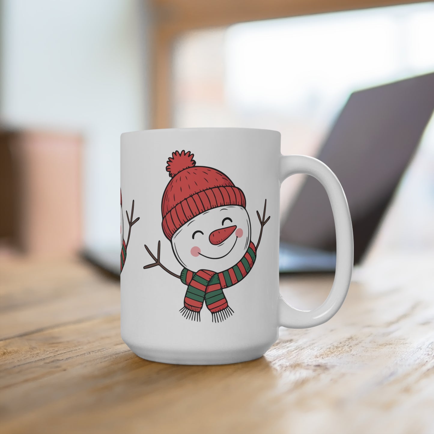 White mug with a snowman design wearing a red hat and striped scarf on a wooden surface.