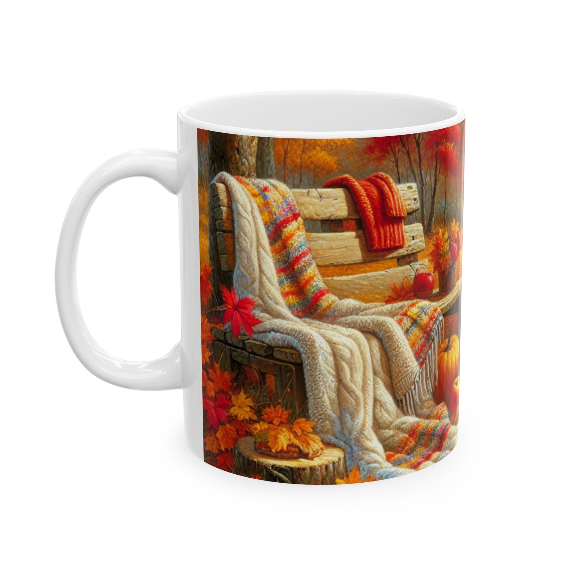 A white ceramic mug with a colorful harvest-themed design featuring a cozy bench, blankets, apples, and a mug of tea. Left Handle