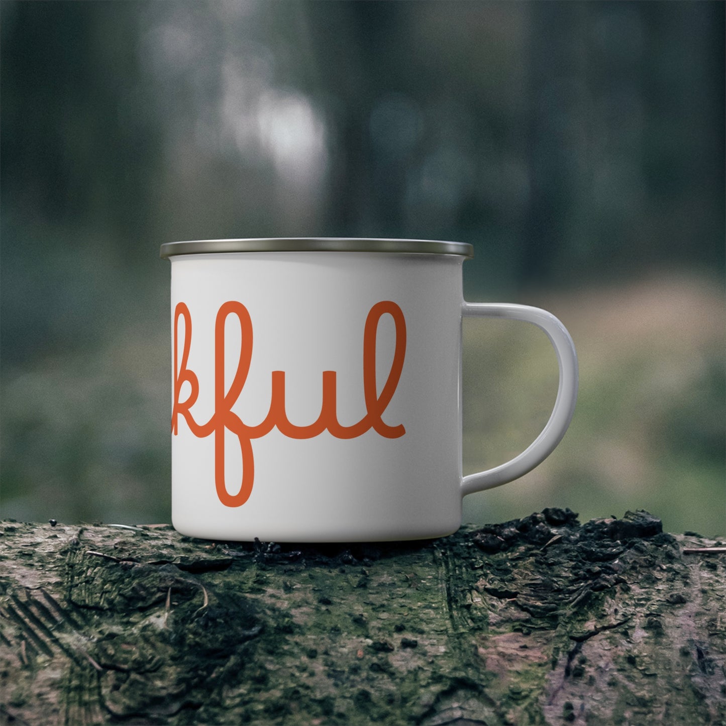 A white stainless steel camping mug with orange 'THANKFUL' text placed on a wooden stump with a hot steam background.