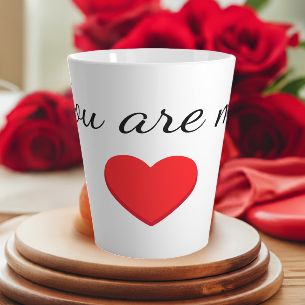 This is a latte mug that says: You are my heart. It stands on some cutting boards red roses in the background. 
